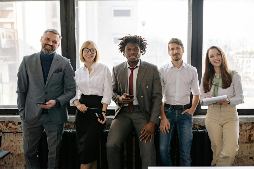 A diverse group of professionals smiling and posing together in a modern office environment.
